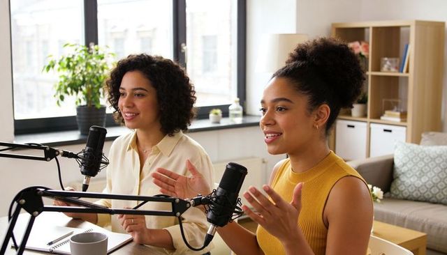 Recording duo hosting podcast in cozy home studio with condenser microphones