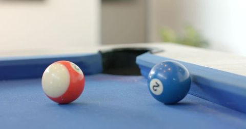 Pool balls resting on blue felt near corner pocket with glossy highlights and depth blur