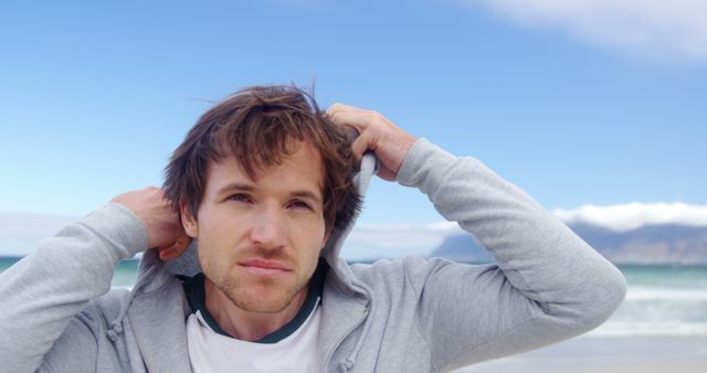 Man Posing on Beach in Hoodie with Clear Skies - Download Free Stock Images Pikwizard.com