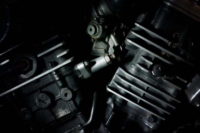 Close-up of engine components in dim light, showcasing intricate mechanical details and metallic surfaces. Ideal for use in automotive industry promotions, mechanical engineering resources, educational materials on motor parts, technical training content, and technology advertisements.