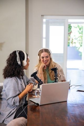Female co-hosts engaging in podcast recording session at home