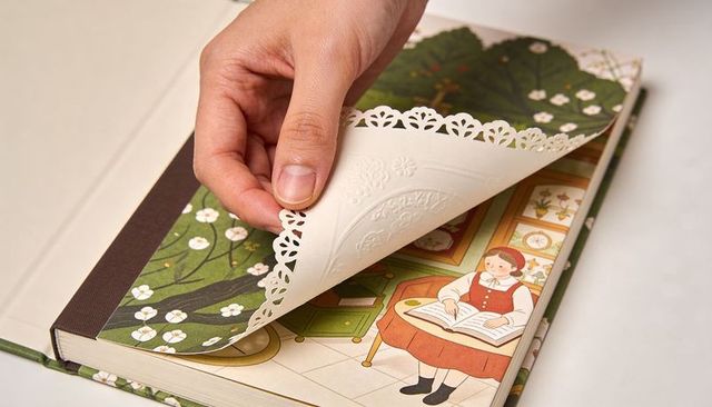 Hand turning die-cut embossed endpaper revealing vintage children's illustration