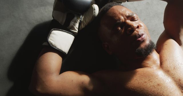 Image of fit and tired african american man after boxing training at gym. active, fit, sporty and healthy lifestyle, exercising at gym concept.