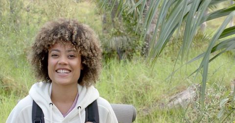 Young Woman Hiking Outdoors with Backpack in Nature, Smiling Confidently