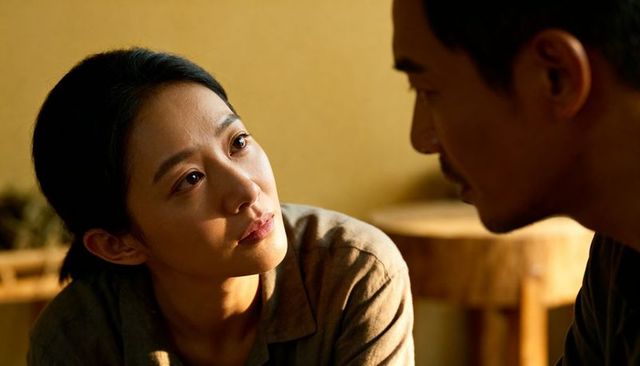 Asian woman listening intently to partner in warm rustic interior, intimate moment