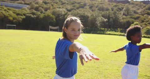 Kids Smiling and Stretching Arms on Sunny Sports Field
