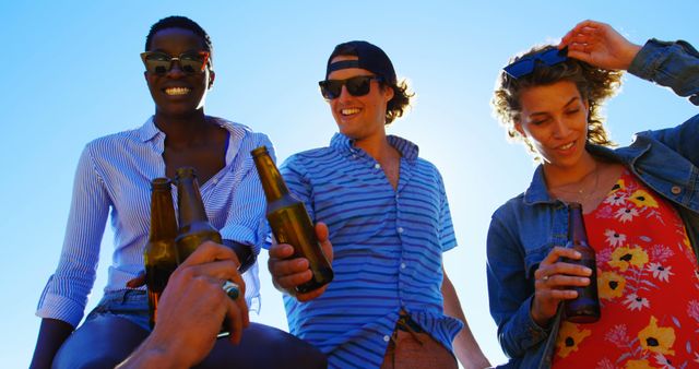 Group of friends having a good time drinking beers together outdoors, perfect for themes of friendship, outdoor events, summer gatherings, celebrations, and social activities.