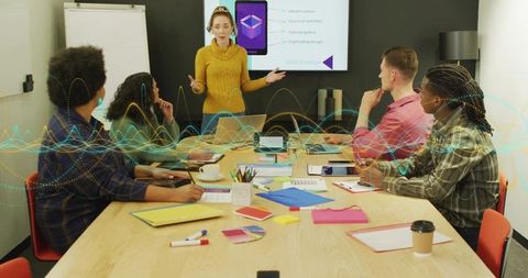 Presenter leading creative team meeting with laptops, color swatches, flipchart and waveform overlay