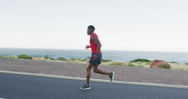 African american man exercising outdoors running on a coastal road. fitness training and healthy outdoor lifestyle.