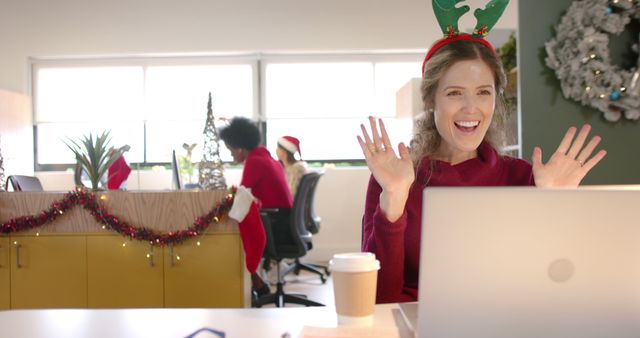 Smiling Woman in Festive Office Waving During Virtual Christmas Celebration - Download Free Stock Images Pikwizard.com