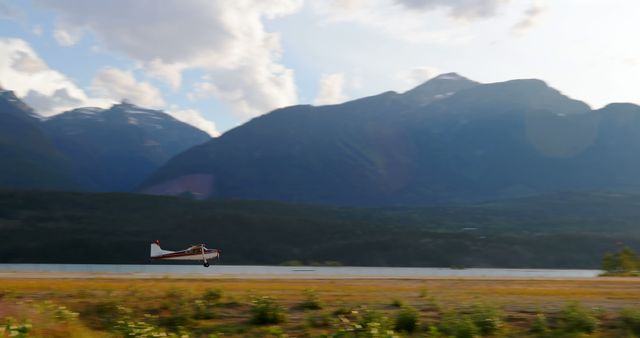 A small airplane is in the process of taking off from a runway surrounded by majestic mountains and a clear sky. The sense of adventure is palpable as the aircraft prepares to soar into the vastness of the natural landscape.