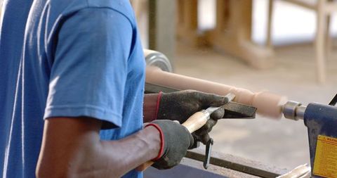 Artisan operating lathe in woodworking shop with precision