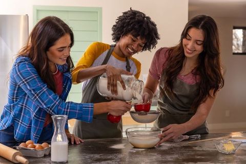 Diverse friends enjoying baking together in kitchen