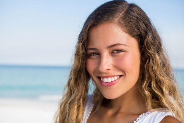 Portrait of beautiful smiling woman at beach against blue sky