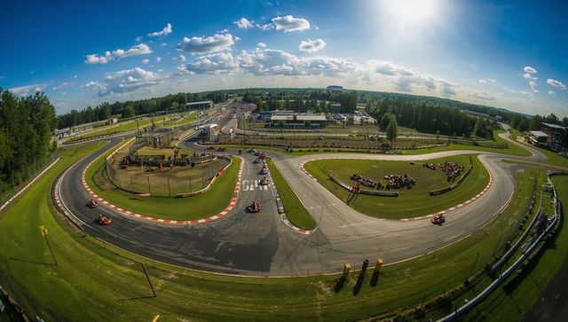 Go-kart racers maneuvering curved asphalt track on sunny day