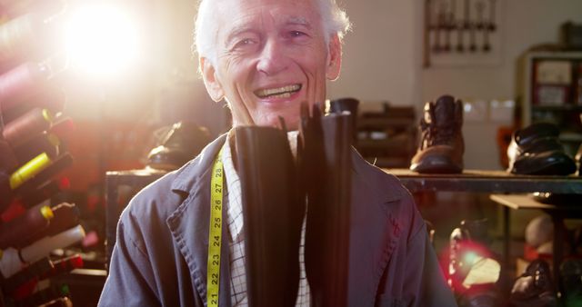 Smiling Senior Shoemaker Holding Boots in Workshop - Download Free Stock Images Pikwizard.com