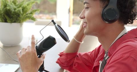 Podcaster Using Microphone with Headphones in Vibrant Home Office
