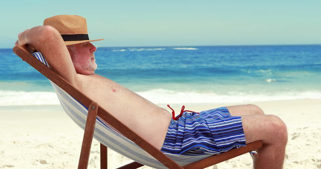 Elderly man enjoying peaceful beach leisure in sunny weather. Ideal for illustrating retirement lifestyles, vacation promotions, travel marketing, beach accessories ads, or depicting relaxation and leisurely activities for seniors.
