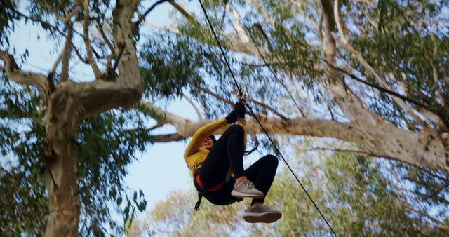 A person enjoys an exhilarating zip line adventure through a forested area, with copy space. Capturing the thrill of outdoor activities, the image conveys a sense of freedom and excitement.