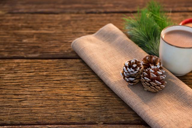Pine cone, coffee cup, sweet food, and christmas fir with napkin on wooden plank