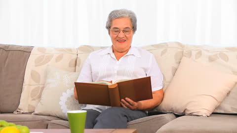 Senior Woman Enjoying Memories in Photo Album on Couch