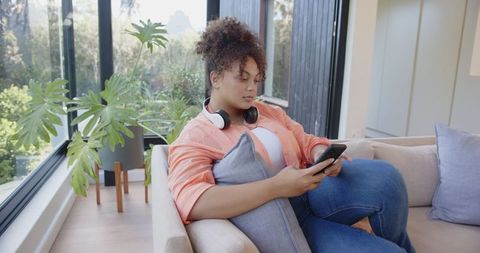 Relaxed Young Woman with Headphones Using Smartphone in Modern Living Room