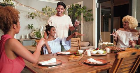 Joyful Friends Enjoying Outdoor Dinner with Laughter and Toasts