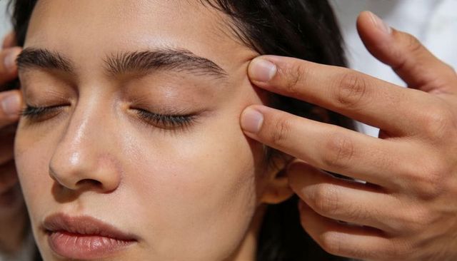 Receiving relaxing temple and brow facial massage, close-up natural skincare treatment