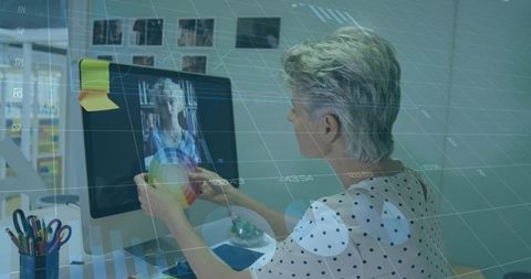 Mature Designer Holding Color Wheel During Remote Consultation with Digital Data Overlay