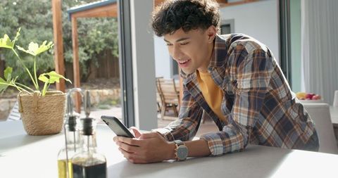 Young person using smartphone in modern kitchen interior