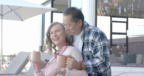 Senior Couple Enjoying Warm Drinks on Contemporary Sunny Terrace