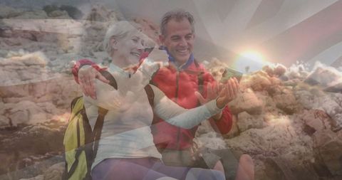 Senior couple taking selfie on rocky coast with backpacks