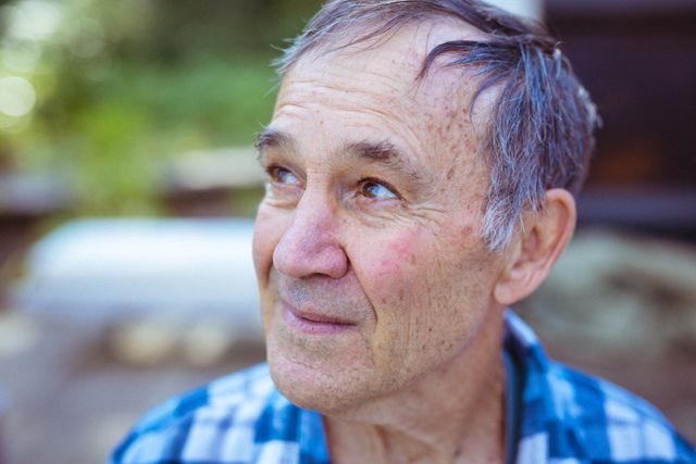 This image captures a happy senior man looking into the distance while outdoors. Ideal for use in articles or advertisements related to retirement, healthy aging, senior lifestyle, and outdoor activities for the elderly. Perfect for illustrating concepts of contentment, peace, and active living in older age.