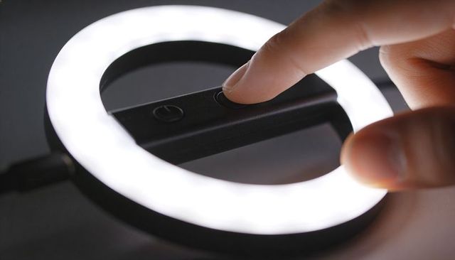 Finger pressing led ring light control closeup emitting cool white glow for video lighting