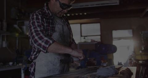 Metalworker grinding in workshop with safety gear