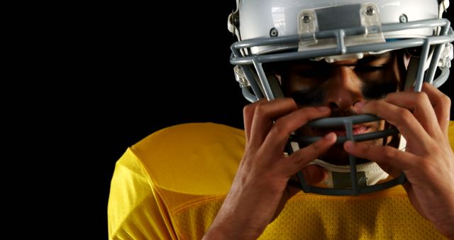 Football Player Wearing Helmet in Yellow Jersey Adjusting His Facemask - Download Free Stock Images Pikwizard.com