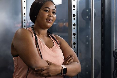 African american woman pausing between strength training sets at gym squat rack