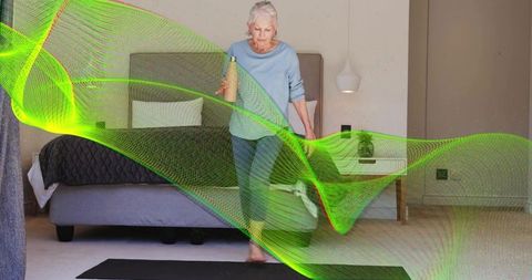Senior woman walking barefoot on bedroom mat holding water bottle under green health wave