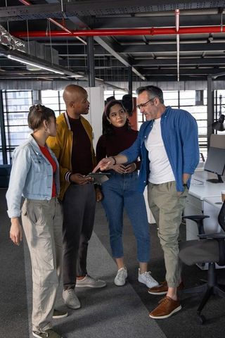 Multicultural team collaborating around tablet in modern open-plan office brainstorming session