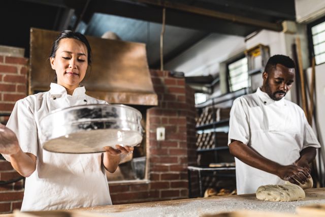 Multiracial baking coworkers preparing dough at kitchen counter in bakery. unaltered, blue-collar worker, skilled, food and drink industry concept.