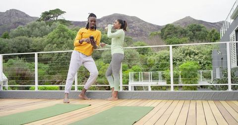 African American man and Indian woman practicing rooftop yoga and wellness on deck