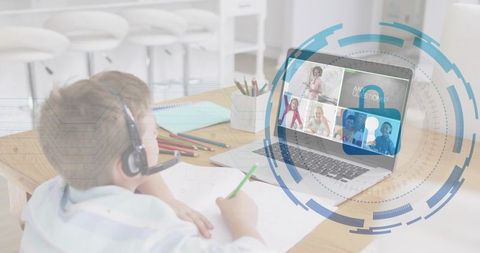 Young boy wearing headset studying online at home with laptop in virtual classroom