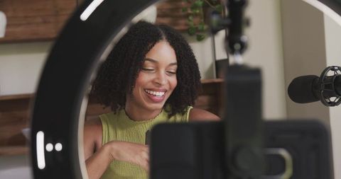 African american creator smiling while recording livestream with ring light and microphone