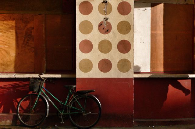 Vintage green bicycle resting against a distressed wall featuring a decorative polka dot design. Captures a sense of nostalgia, urban decay, and the passage of time. Ideal for use in themes related to city life, urban exploration, and minimalist photography.