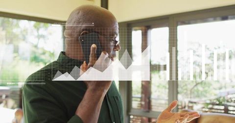 Senior professional talking on phone reviewing analytics dashboard in home office