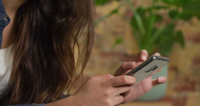 Woman Using Smartphone in Home Environment with Brick Wall and Green Plants - Download Free Stock Images Pikwizard.com