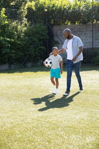 Father and Son Bonding Over Soccer in Sunny Park