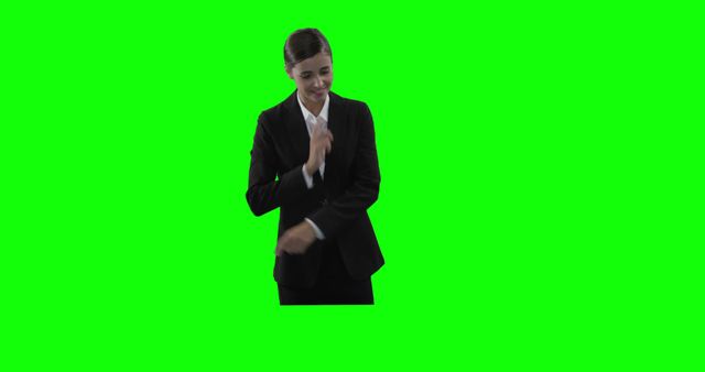 Professional businesswoman adjusting her suit before a green screen. Perfect for corporate presentations, promotional material, videography projects requiring chroma keying, office themes, or advertisements featuring business attire.