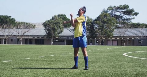 Soccer player stretching on field preparing for practice