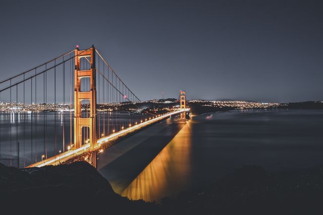Golden Gate Bridge featuring golden lights, extending across the San Francisco Bay at night. Ideal for travel blogs, tourism advertisements, architectural studies, and cityscape projects.